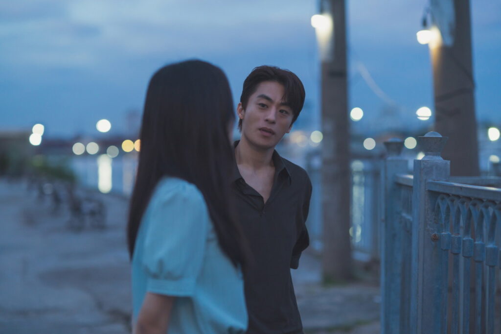 영화 만약에 우리 스틸컷, 해 진 뒤 물가 난간 옆에서 마주 보고 이야기하는 두 사람